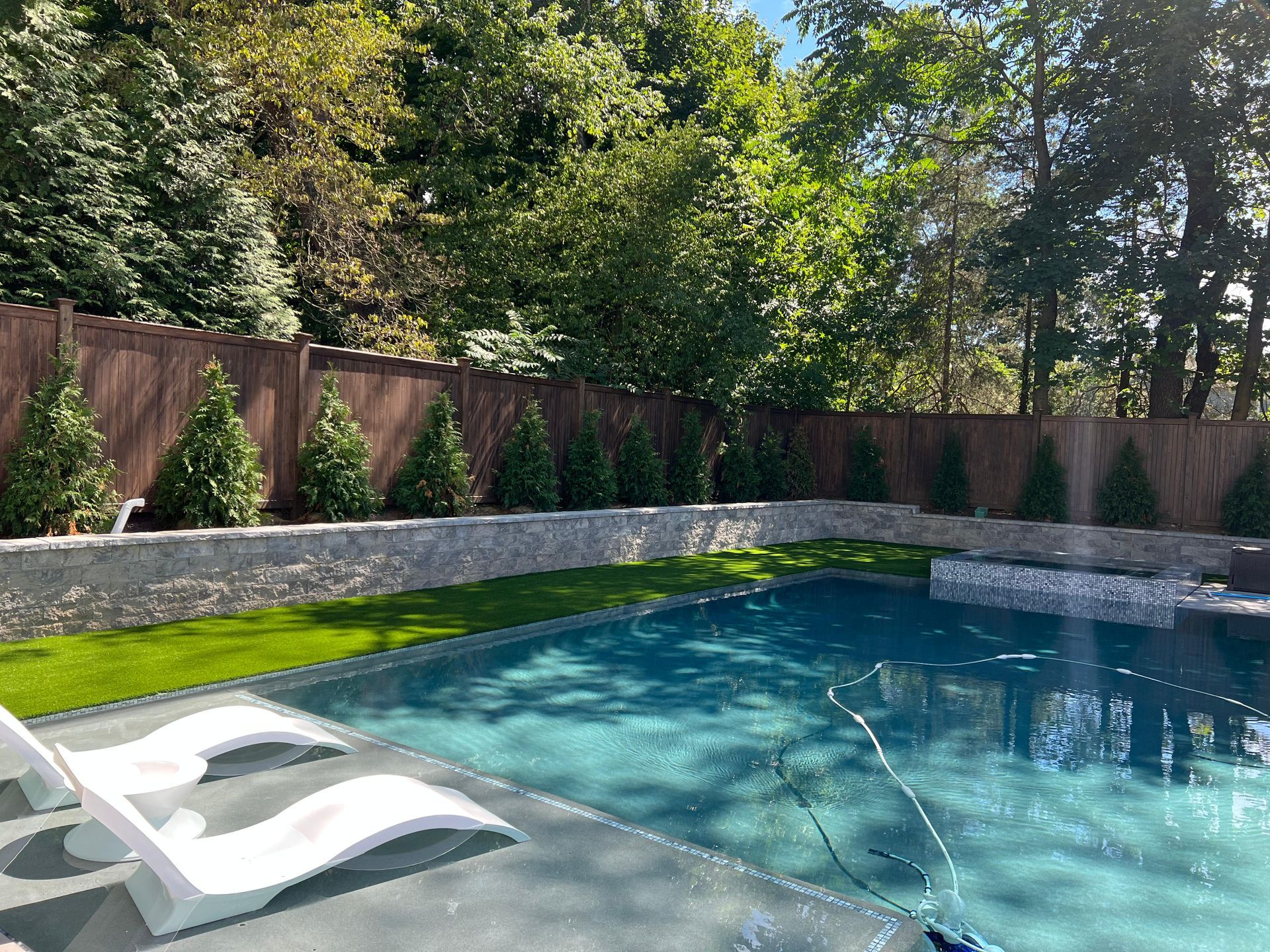 There is a large swimming pool in the backyard with a fence surrounding it.