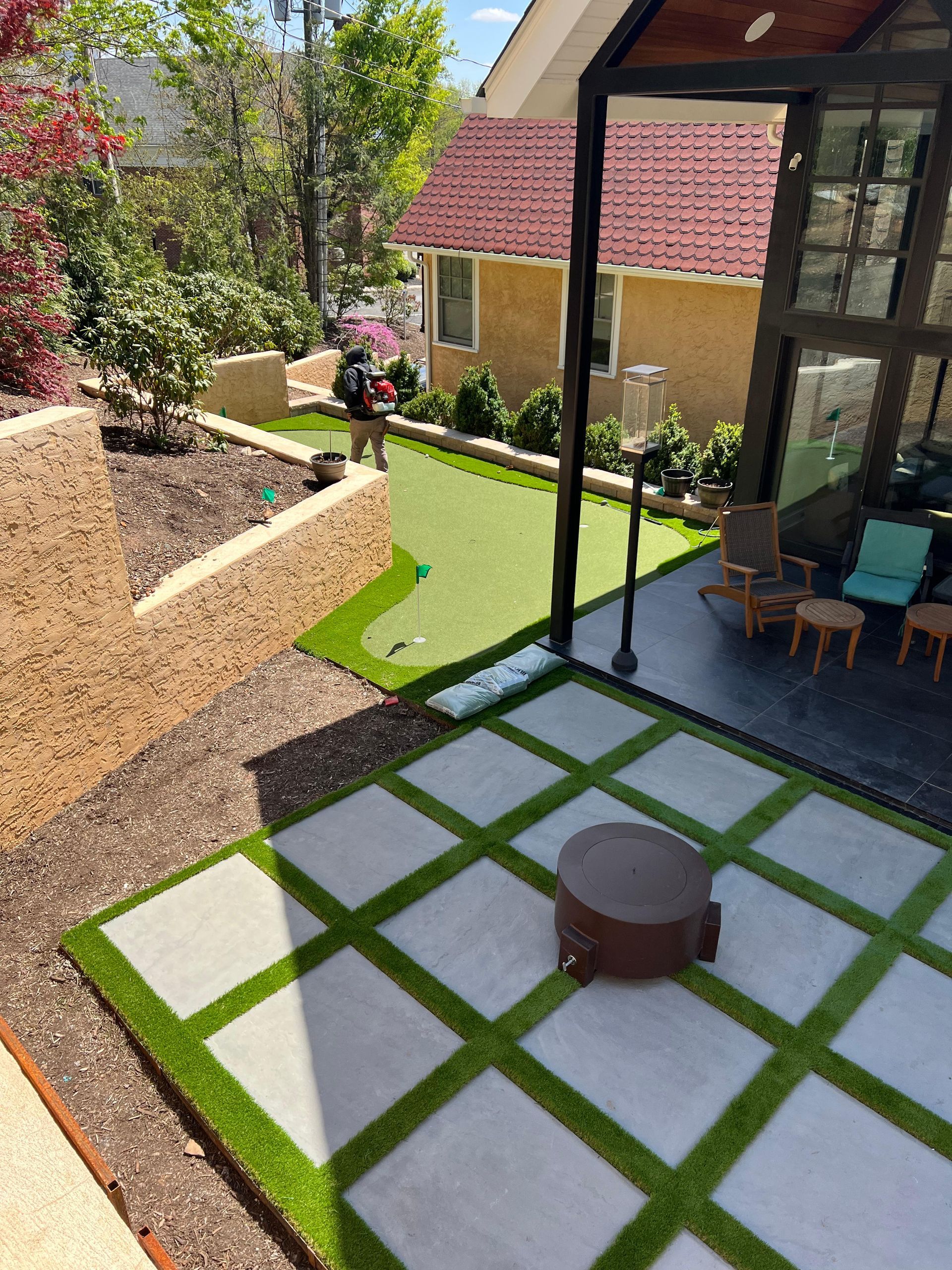 An aerial view of a backyard with a putting green and a fire pit.
