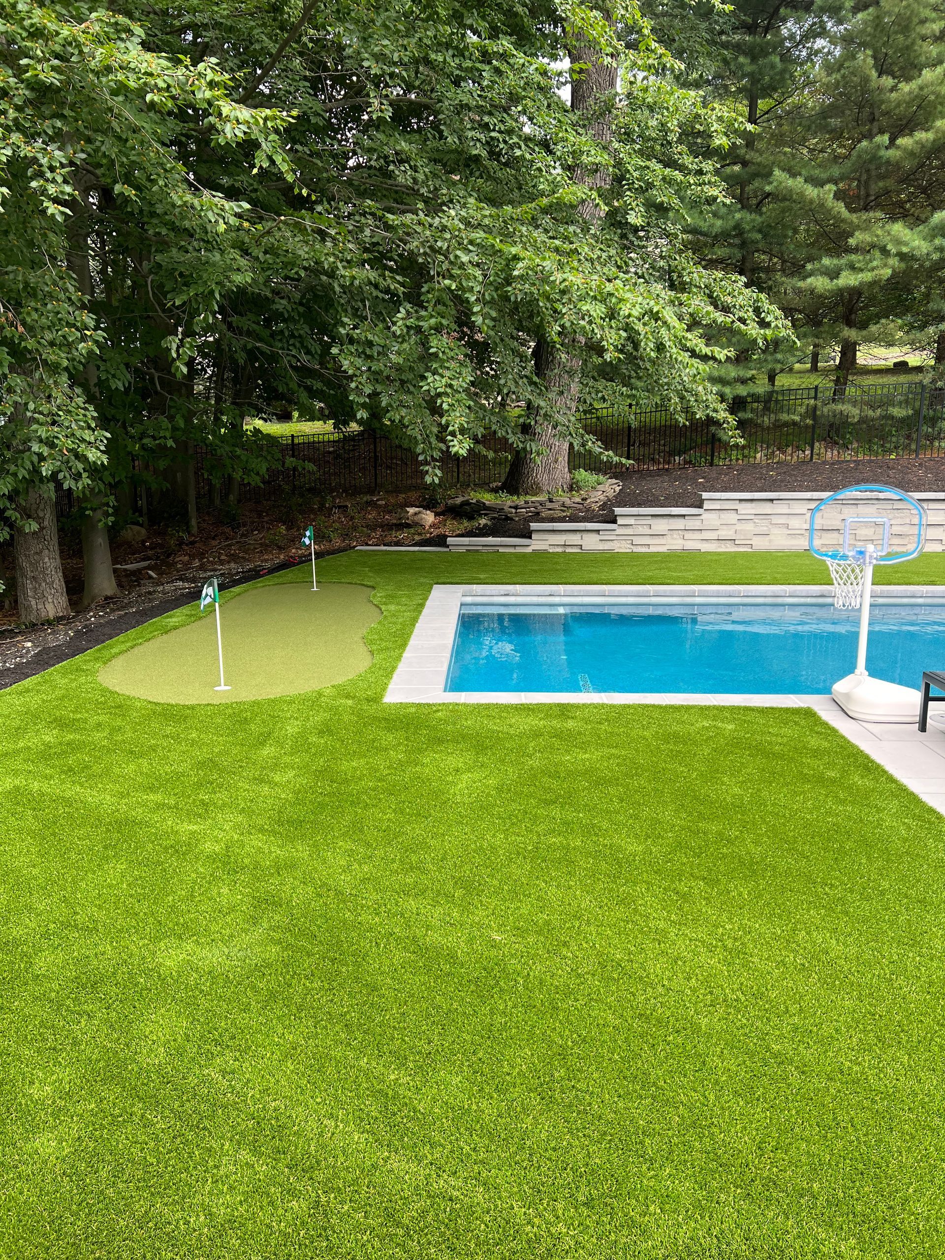 A backyard with a swimming pool and a putting green.