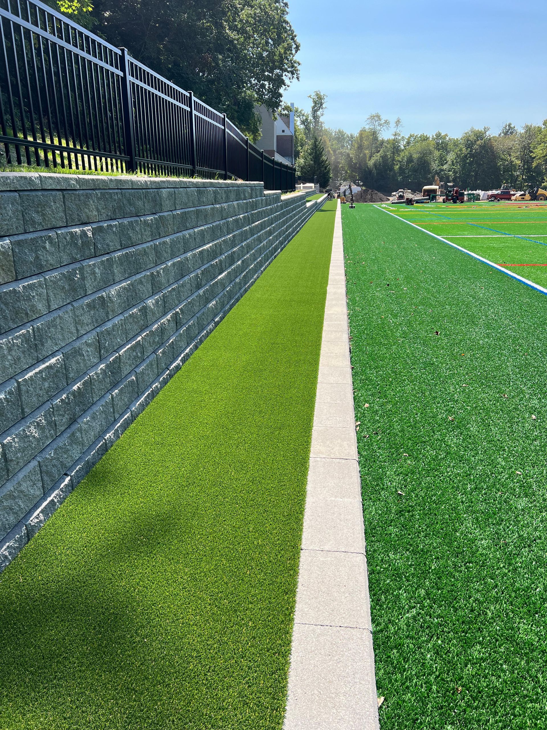A football field with a brick wall and a fence surrounding it.
