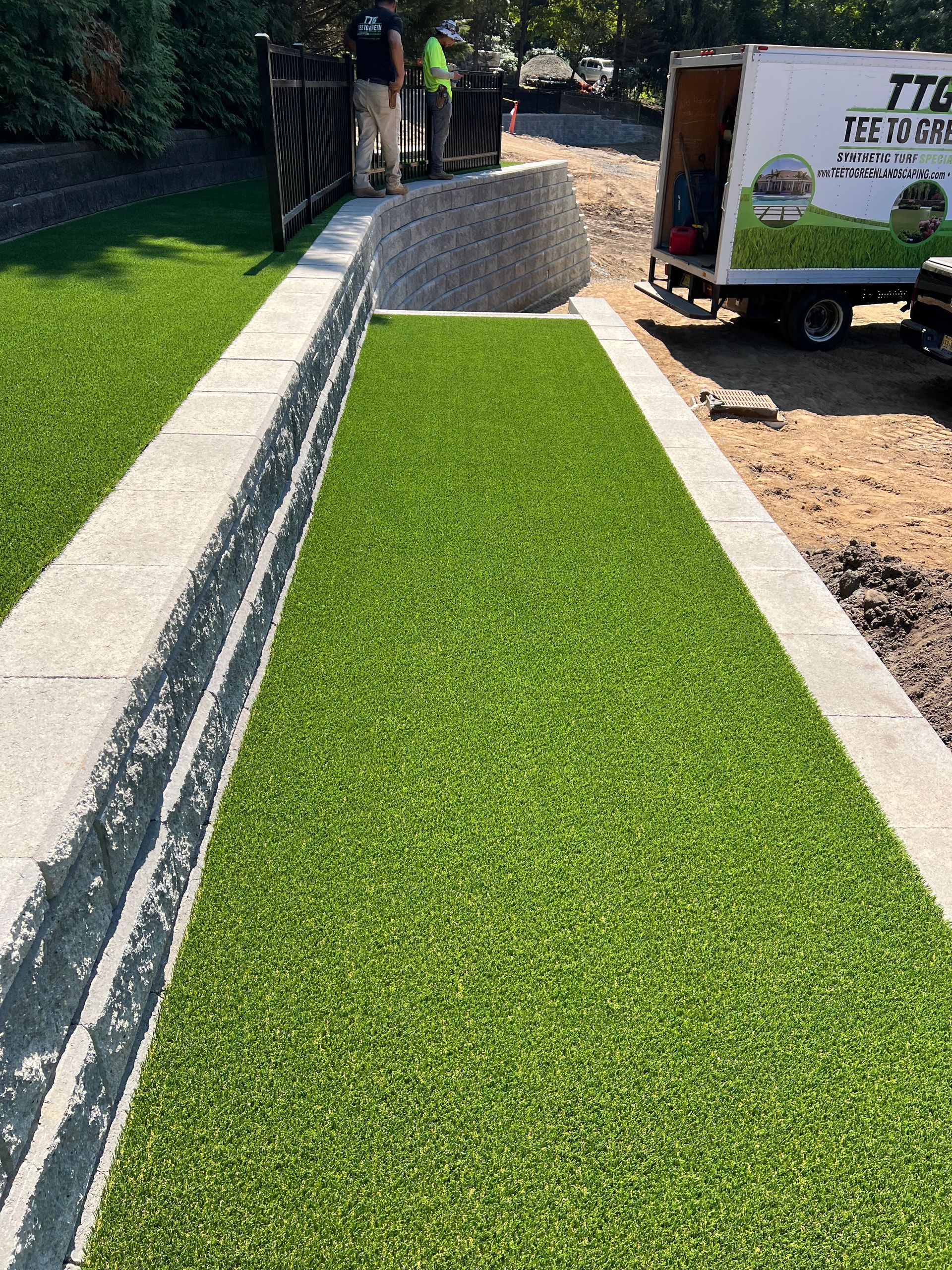 A truck is parked on the side of a road next to a lush green lawn.