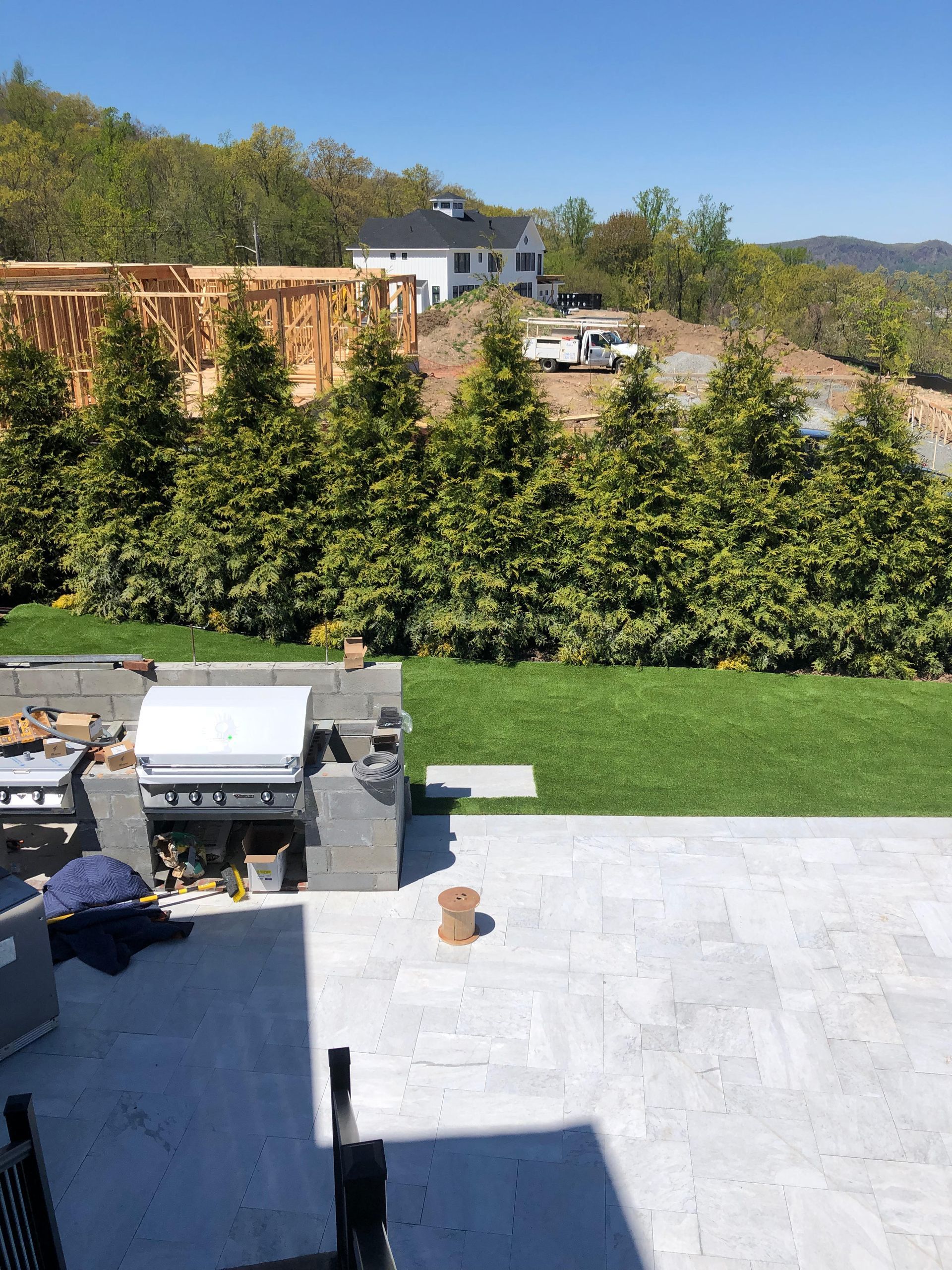A patio with a grill and trees in the background.