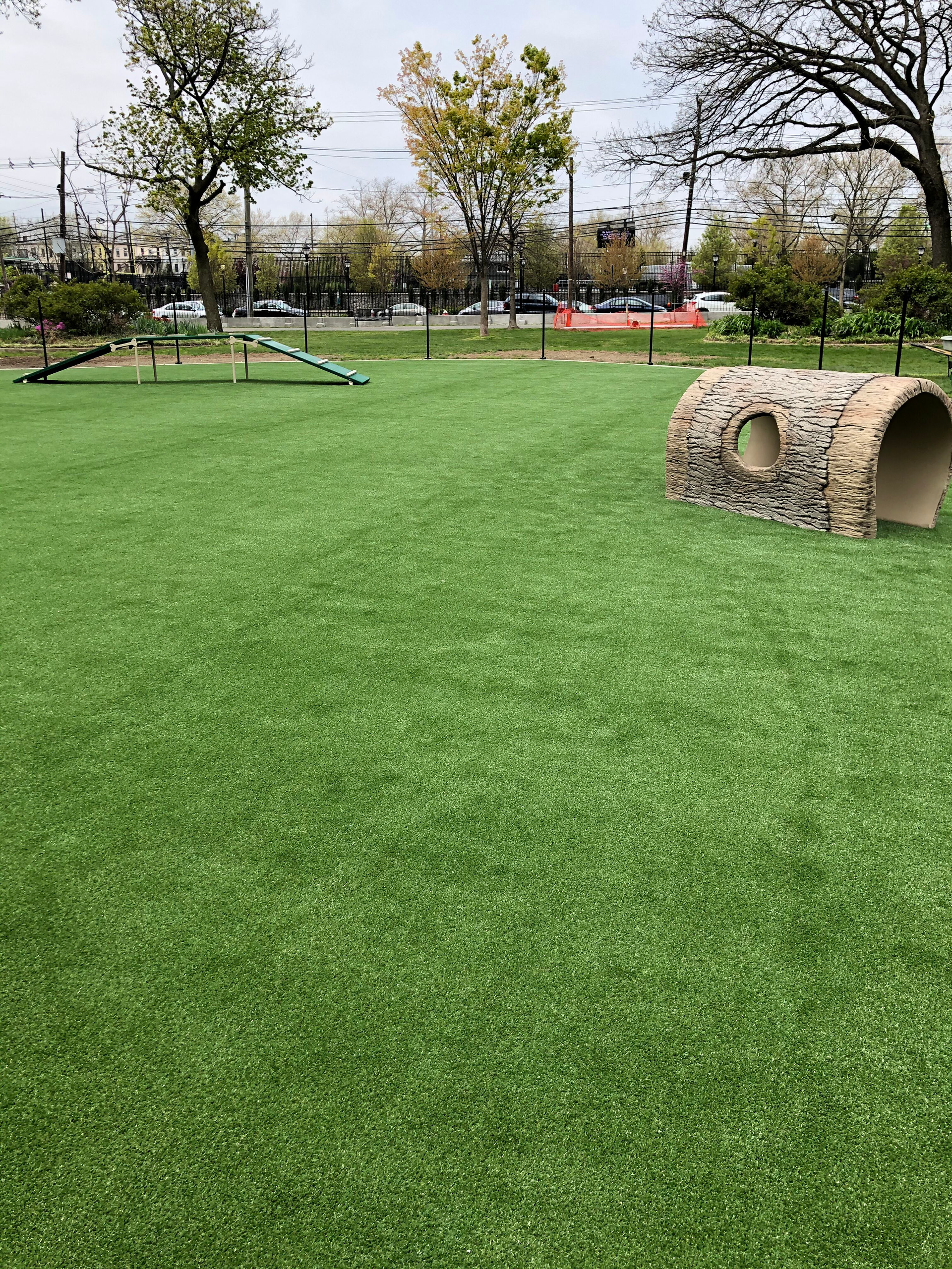 There is a tunnel in the middle of the grass in the park.
