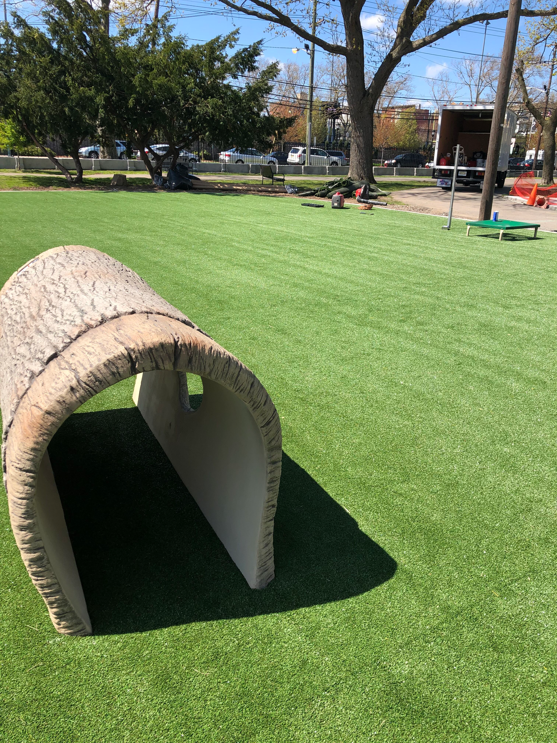 A tunnel made out of a tree trunk is sitting on top of a lush green field.