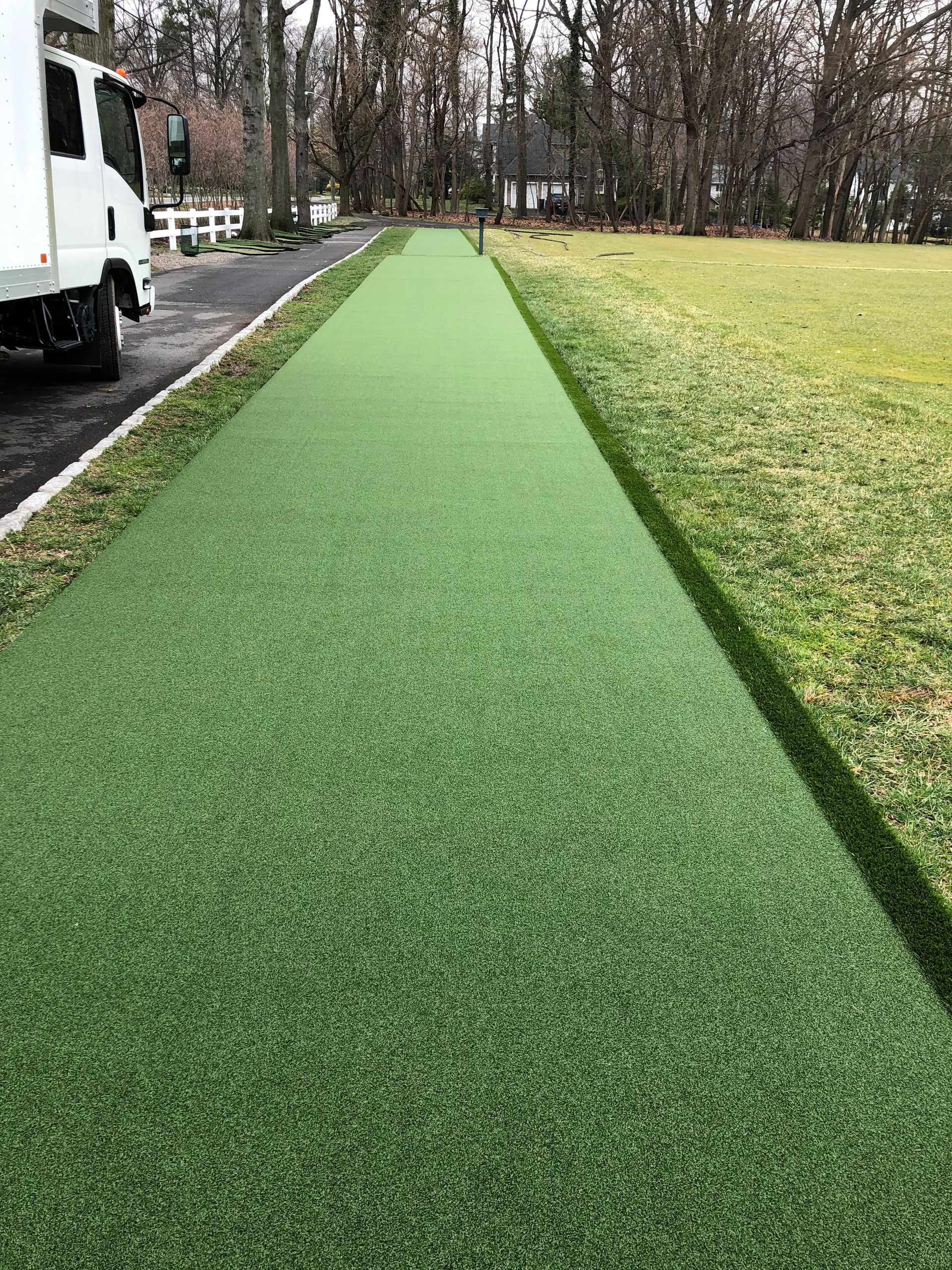 A white truck is parked on the side of a road next to a grassy field.