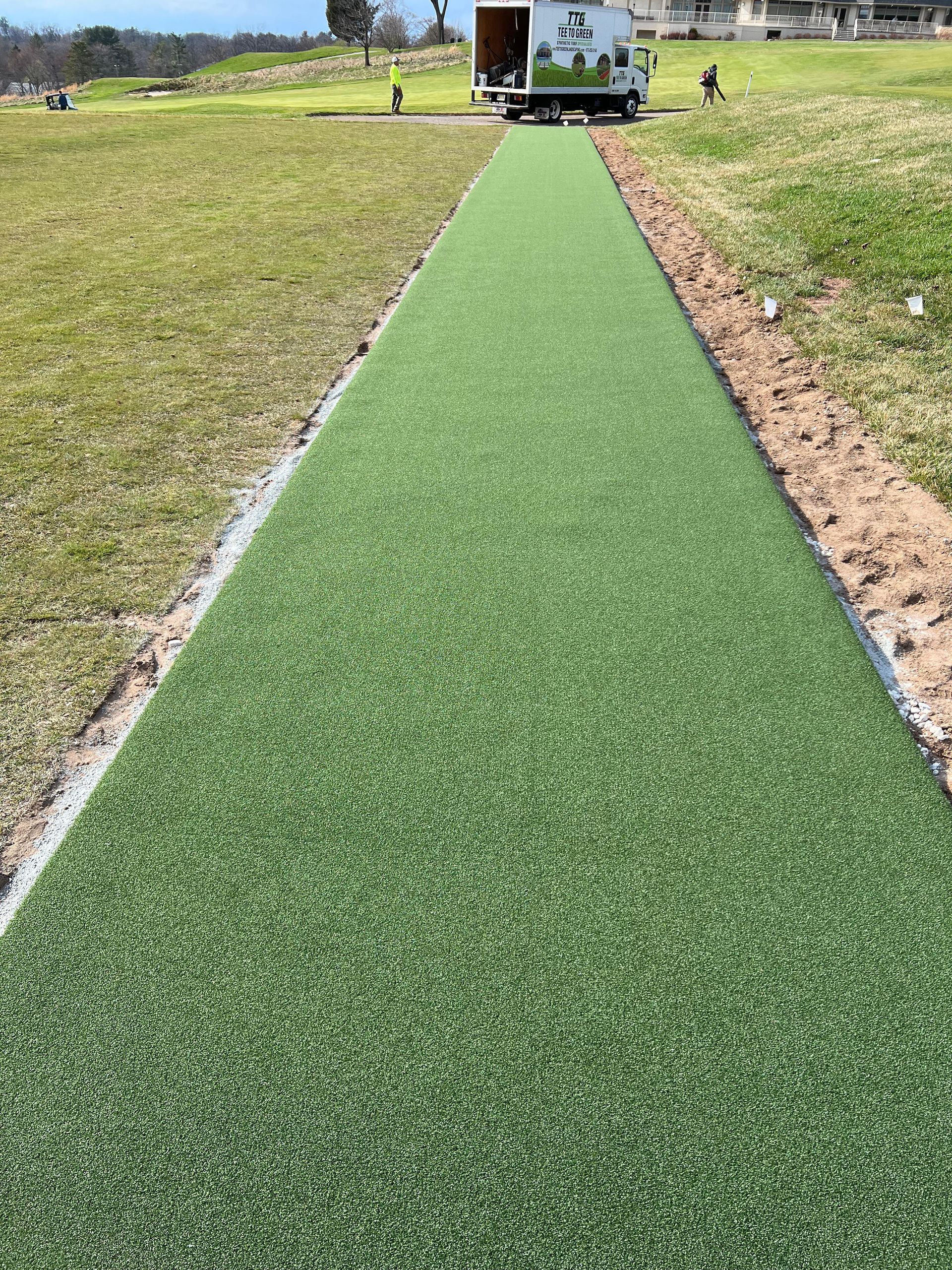 A truck is parked on the side of a grassy field.