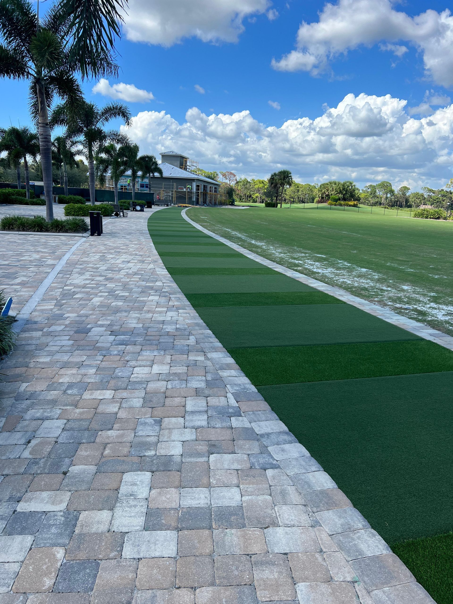 A brick walkway leading to a grassy field.