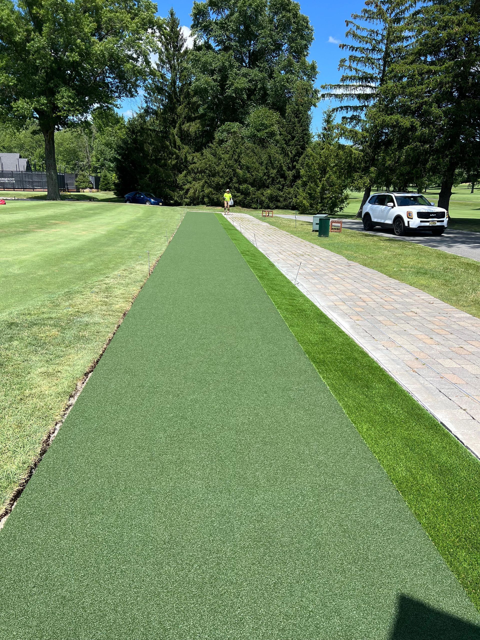A white truck is parked on the side of the road next to a grassy field.