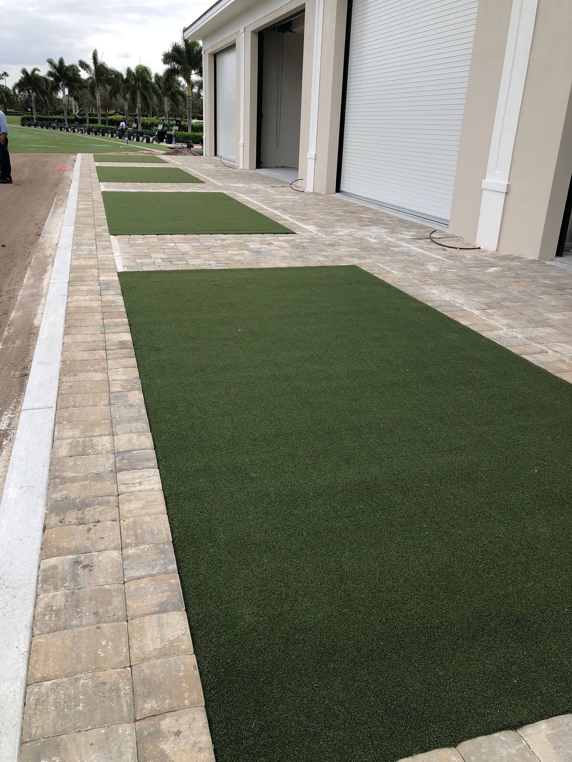 A driveway with a lot of green grass and bricks.