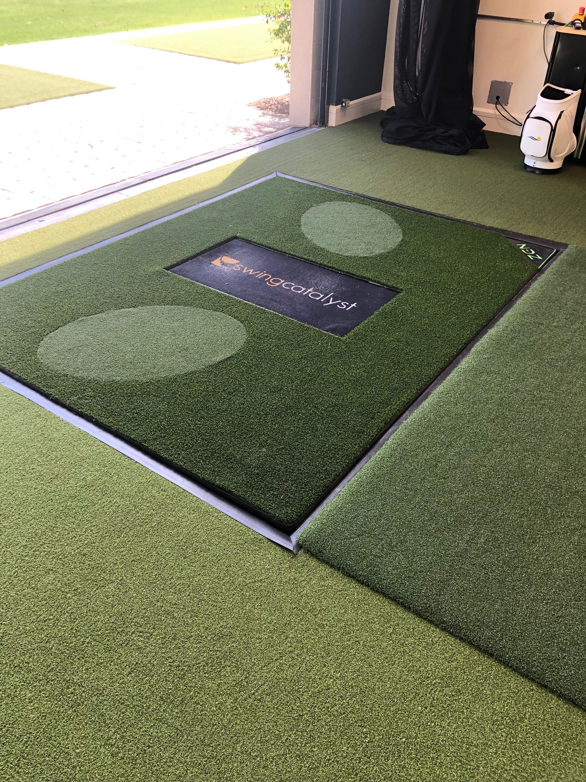 A golf mat is sitting on top of a green carpet.