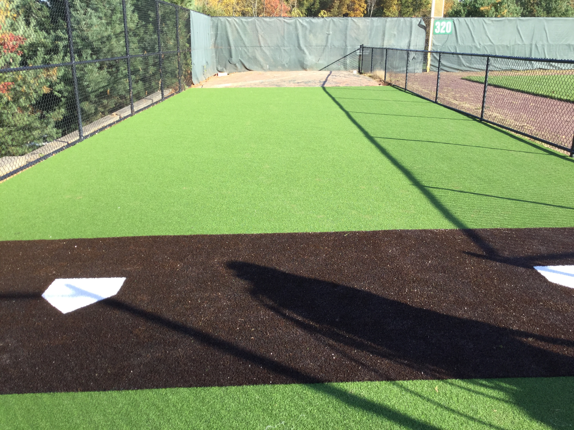 A baseball field with a base and a fence in the background.