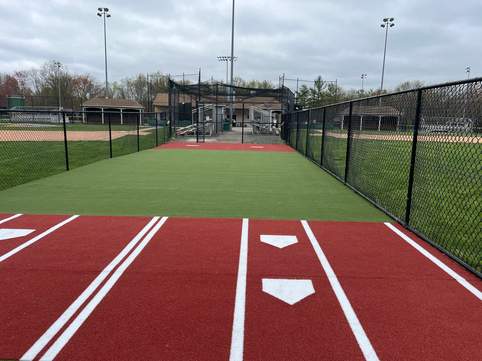 A baseball field with a fence surrounding it and a base painted on the ground.