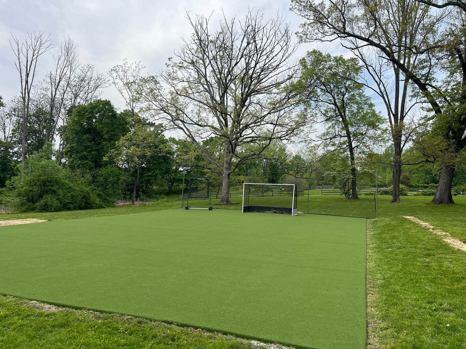 A soccer field in a park with trees in the background.