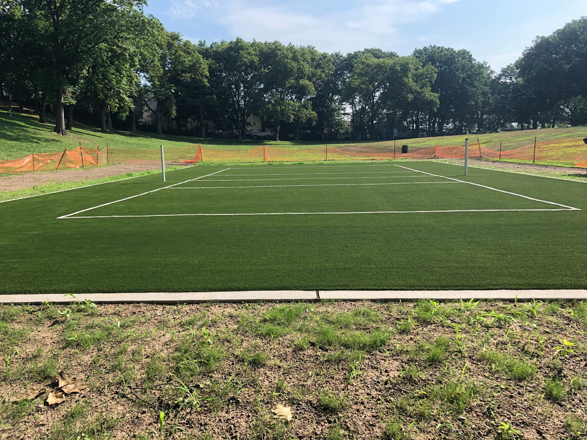 A soccer field with a lot of grass and trees in the background.
