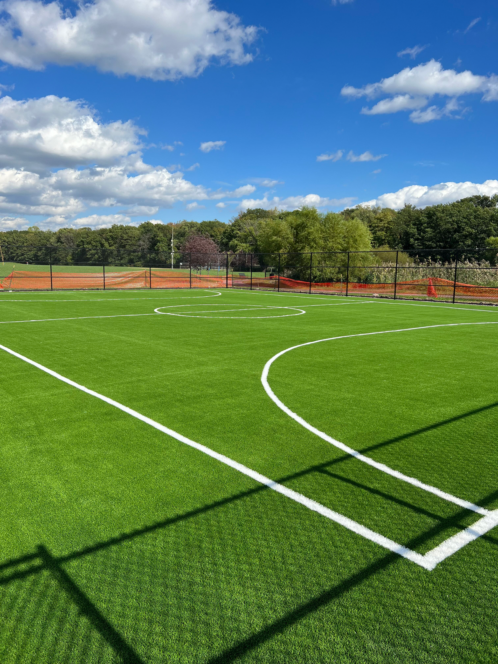 A soccer field with a white line on it on a sunny day.