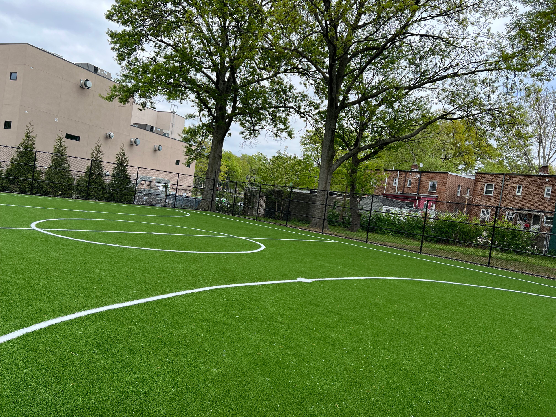 A soccer field with a white line on it and trees in the background.