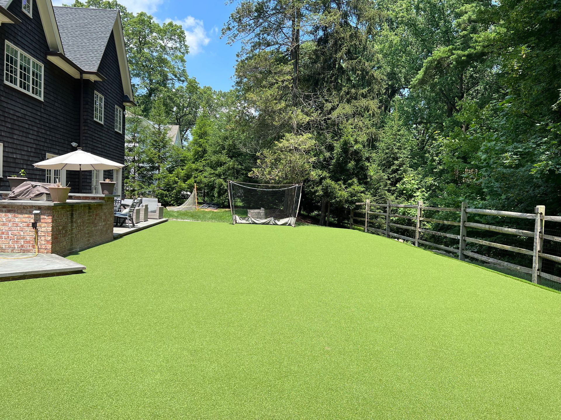 A large lawn with a wooden fence and a house in the background.