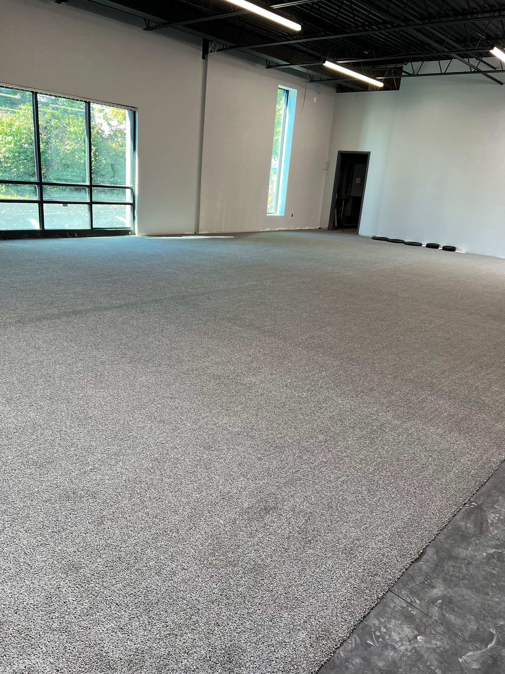 A large room with a carpeted floor and a window.