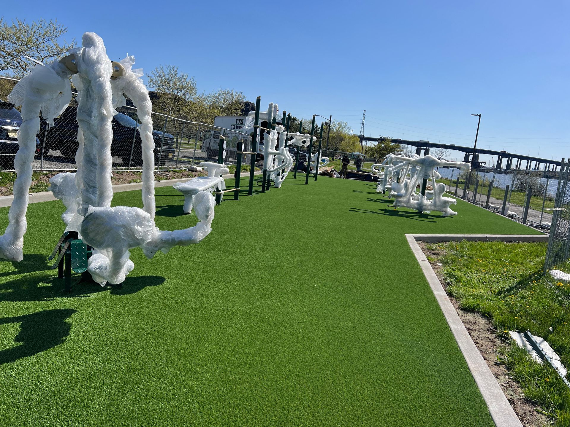 A row of white sculptures are sitting on top of a lush green field.