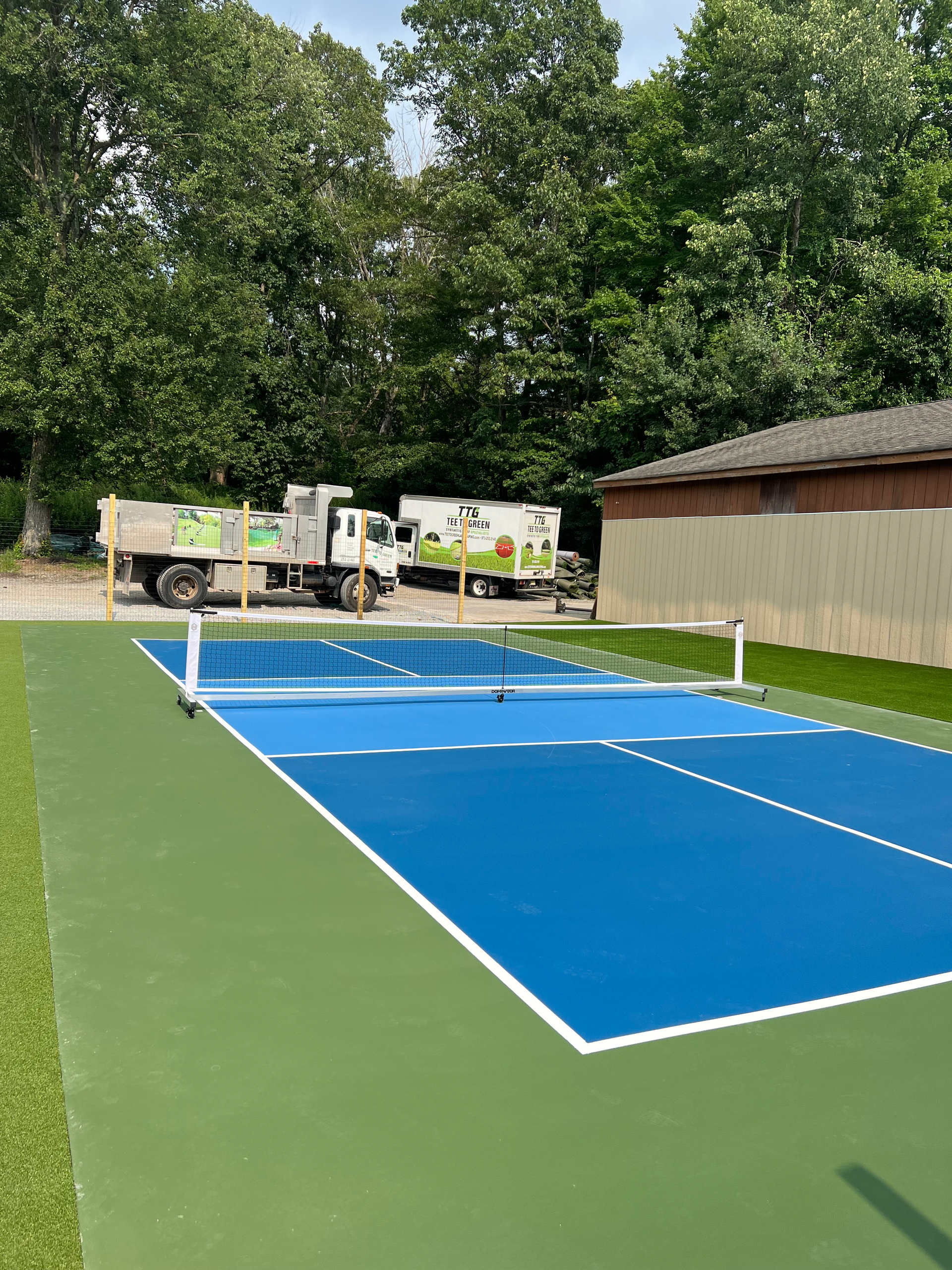 A tennis court with a truck parked in front of it.