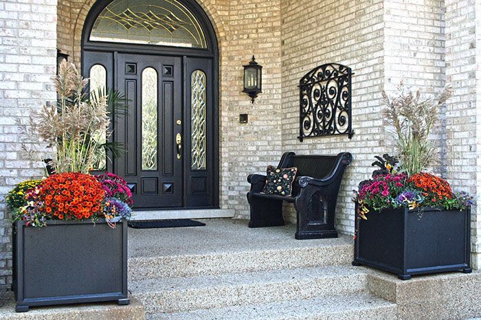 A brick house with a black door and planters with flowers in front of it
