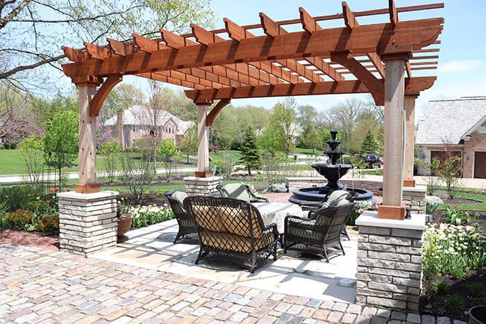 A pergola with a couch and chairs underneath it