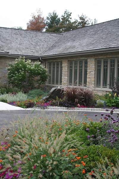A stone house with a lush garden filled with colorful plants.