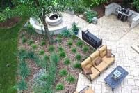 Overhead view of a backyard patio with seating, a fire pit, grill, and landscaping.