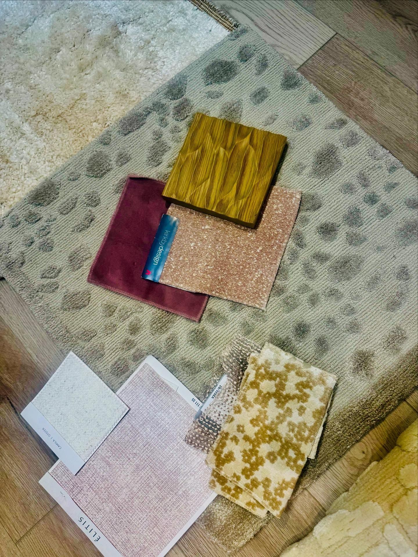 Samples of fabric and carpet, various colors and textures, arranged on a patterned rug.
