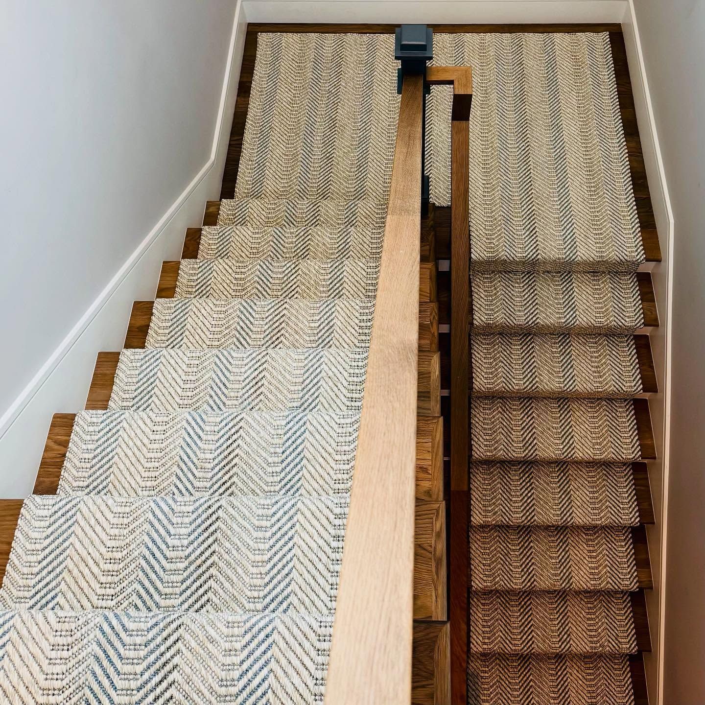 Staircase with woven runner. Wood stairs and handrail. Runner is cream and blue chevron pattern.