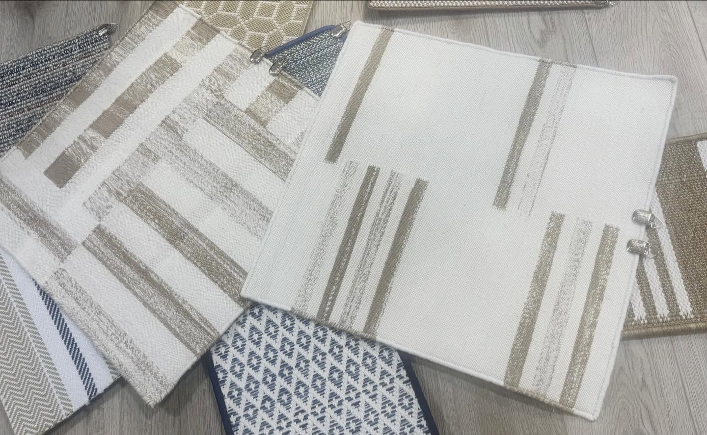 Various textured fabric placemats in white and beige with striped and diamond patterns.