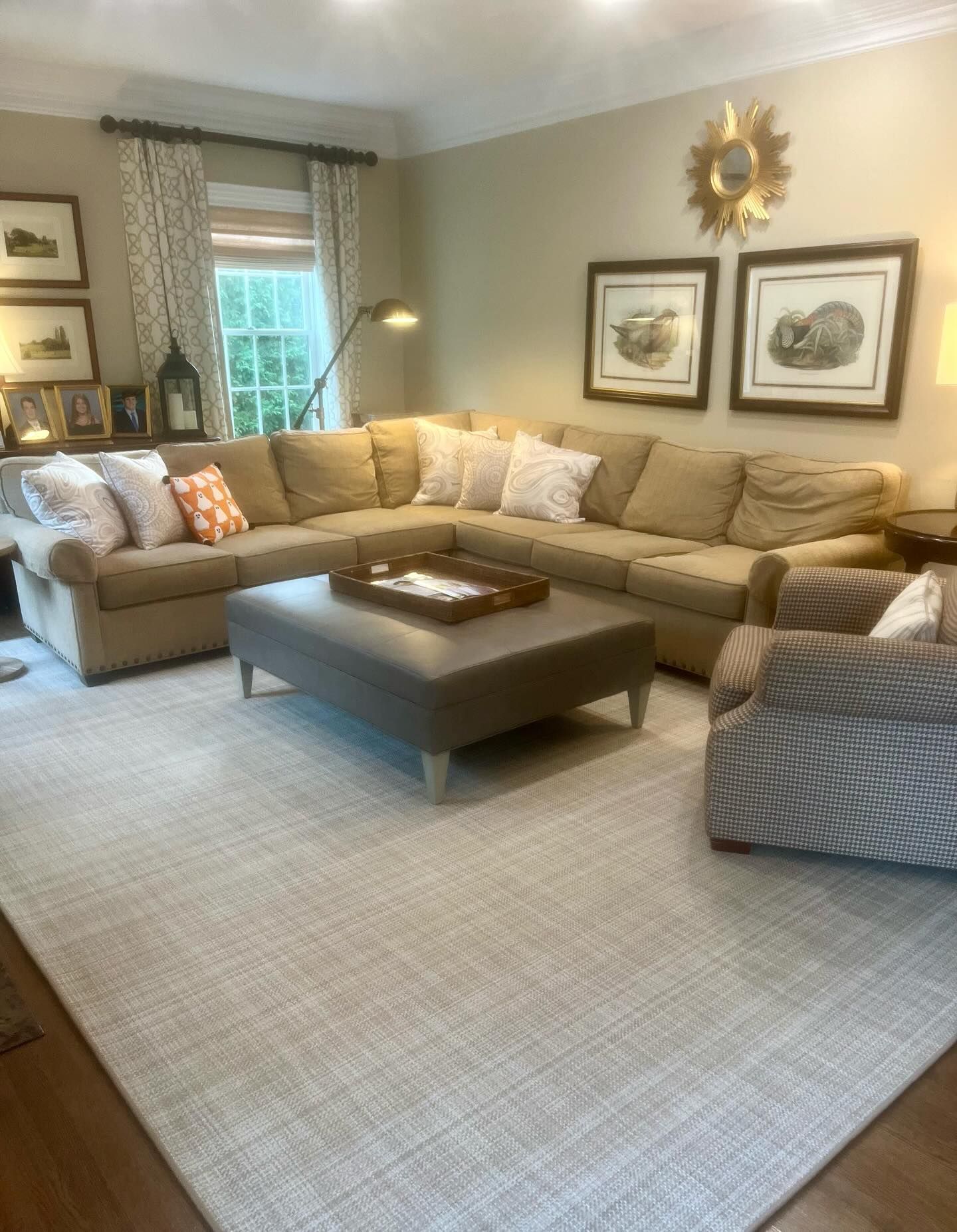 Living room with a large tan sectional, patterned rug, and decorative artwork.