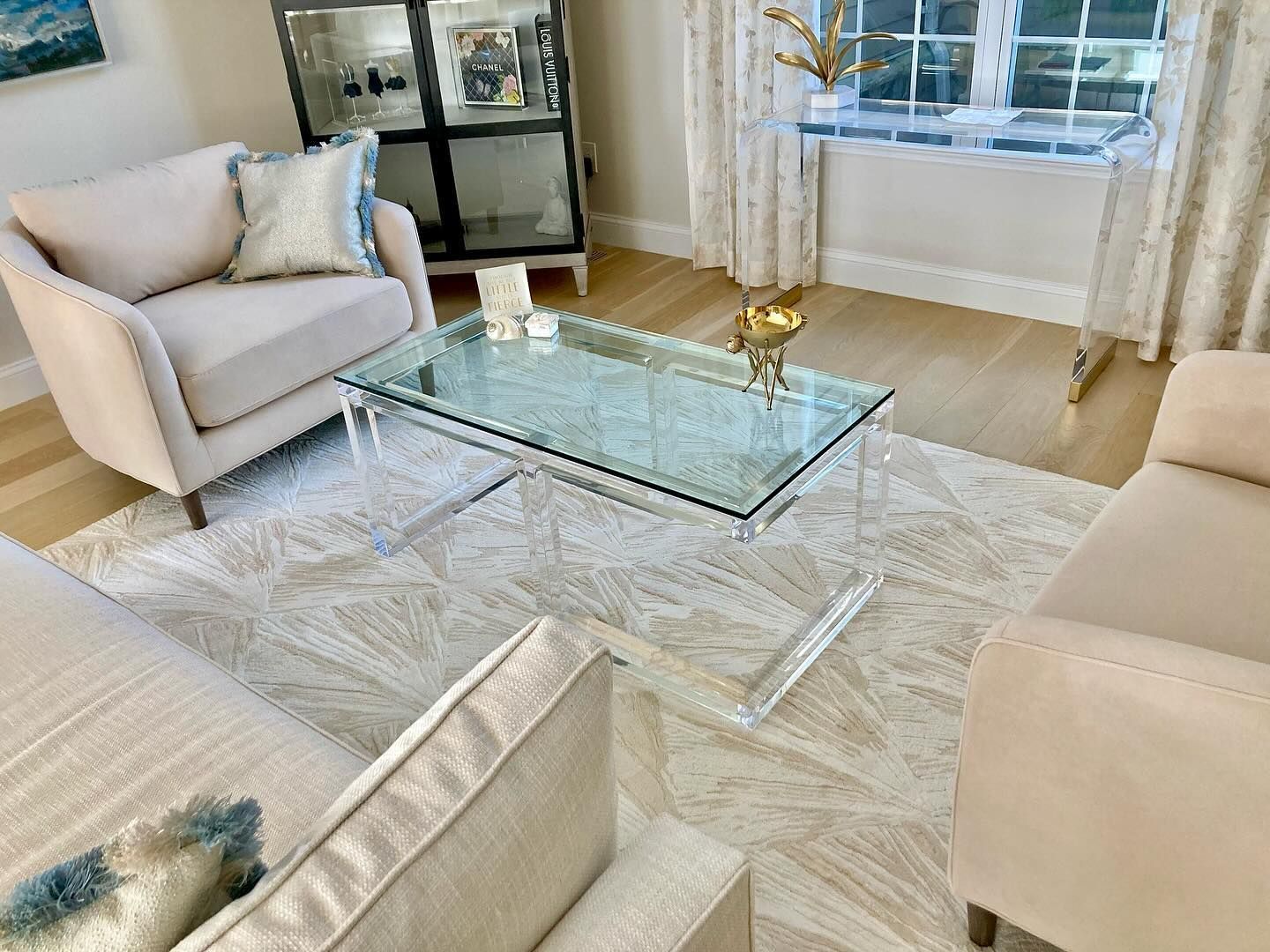Living room with beige furniture, glass coffee table, and patterned rug.