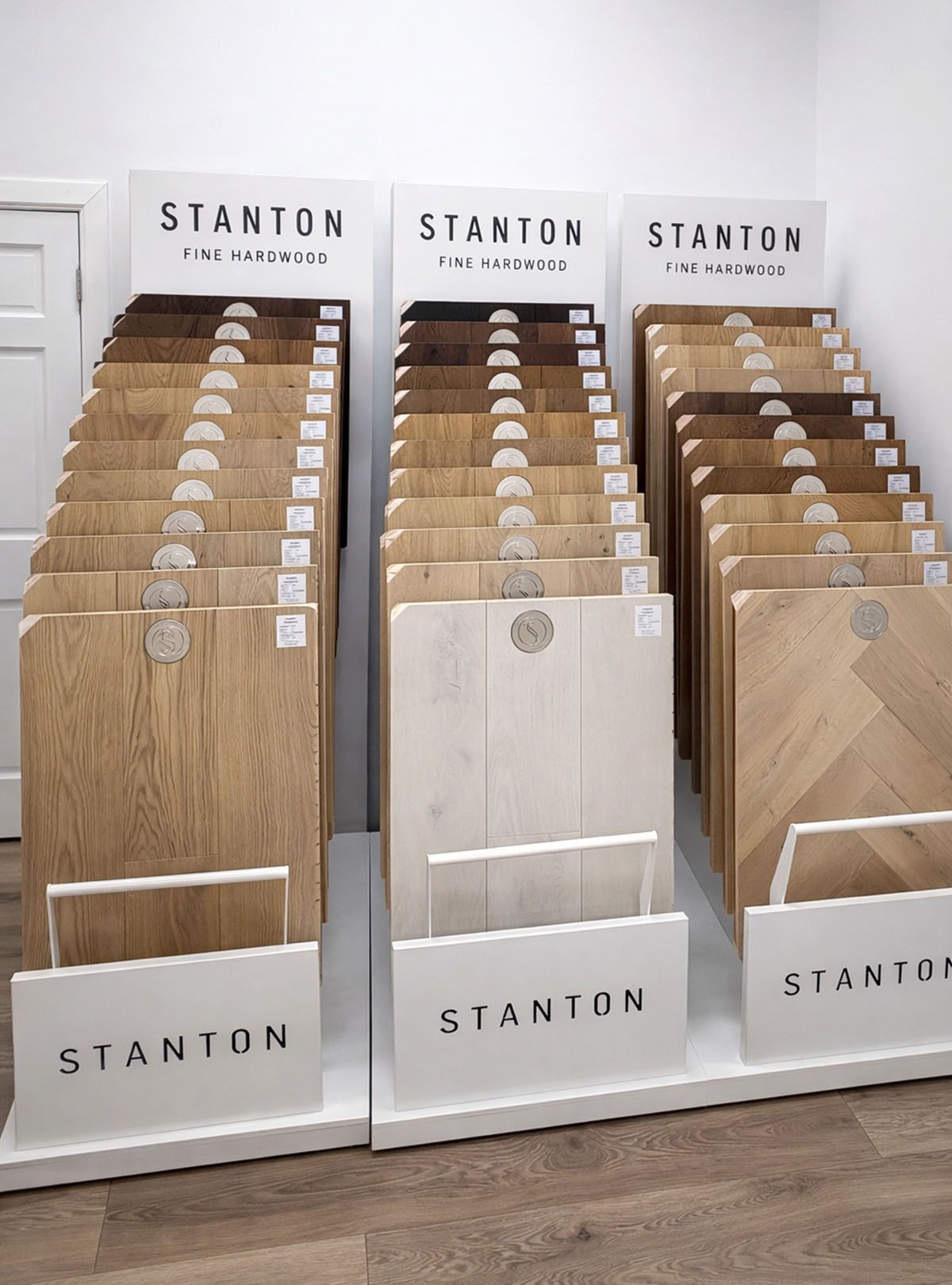 Three display racks of Stanton flooring samples, featuring various wood finishes arranged in rows