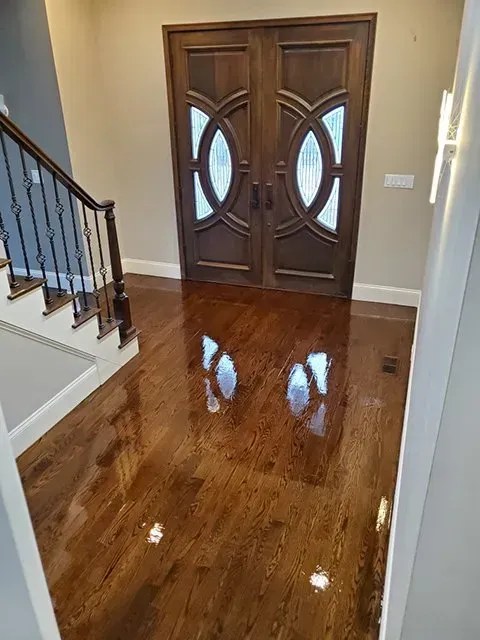 A hallway with hardwood floors, stairs and a door.