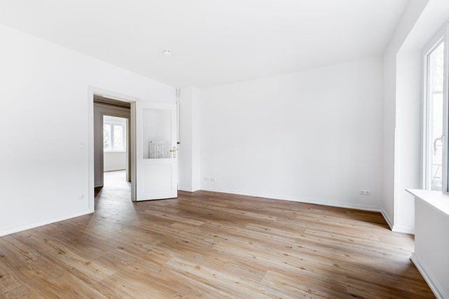 An empty living room with wooden floors and white walls.