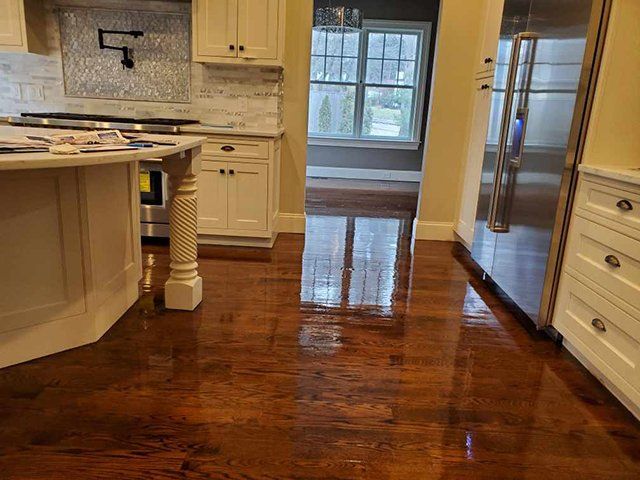 A kitchen with hardwood floors , white cabinets and stainless steel appliances.