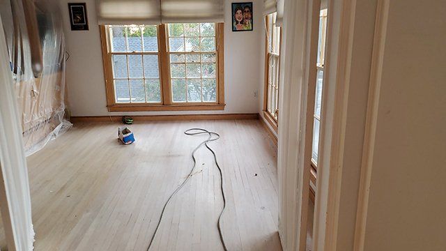 A room with a lot of windows and a vacuum cleaner on the floor.
