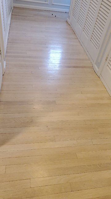 A hallway with hardwood floors and white shutters.