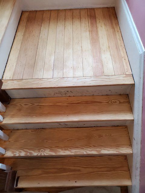A set of wooden stairs with a wooden floor.