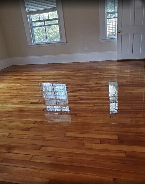 A living room with hardwood floors and two windows.