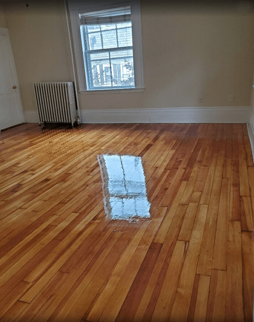 An empty room with hardwood floors and a window