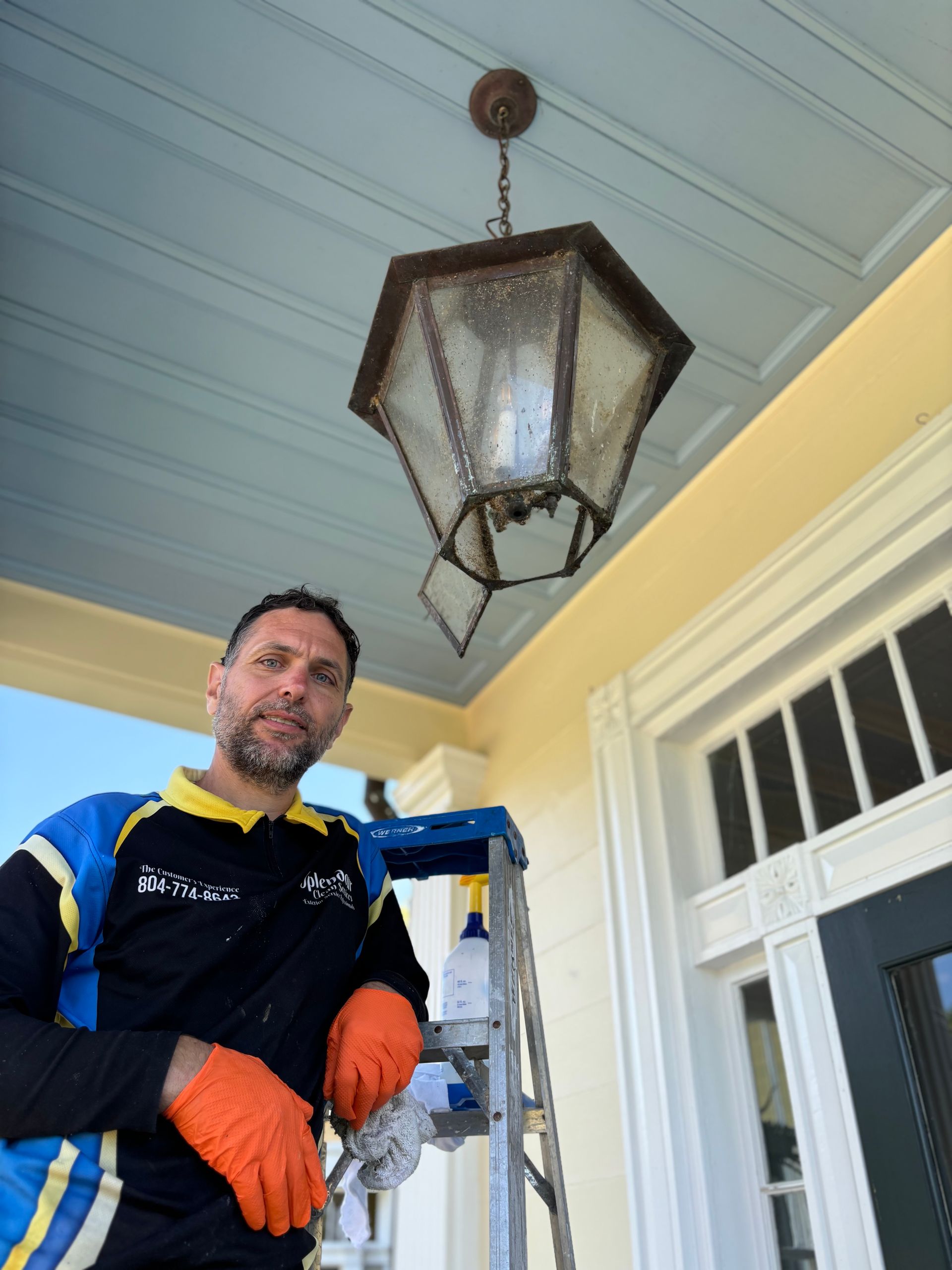 A man standing on a ladder with a lantern hanging from the ceiling
