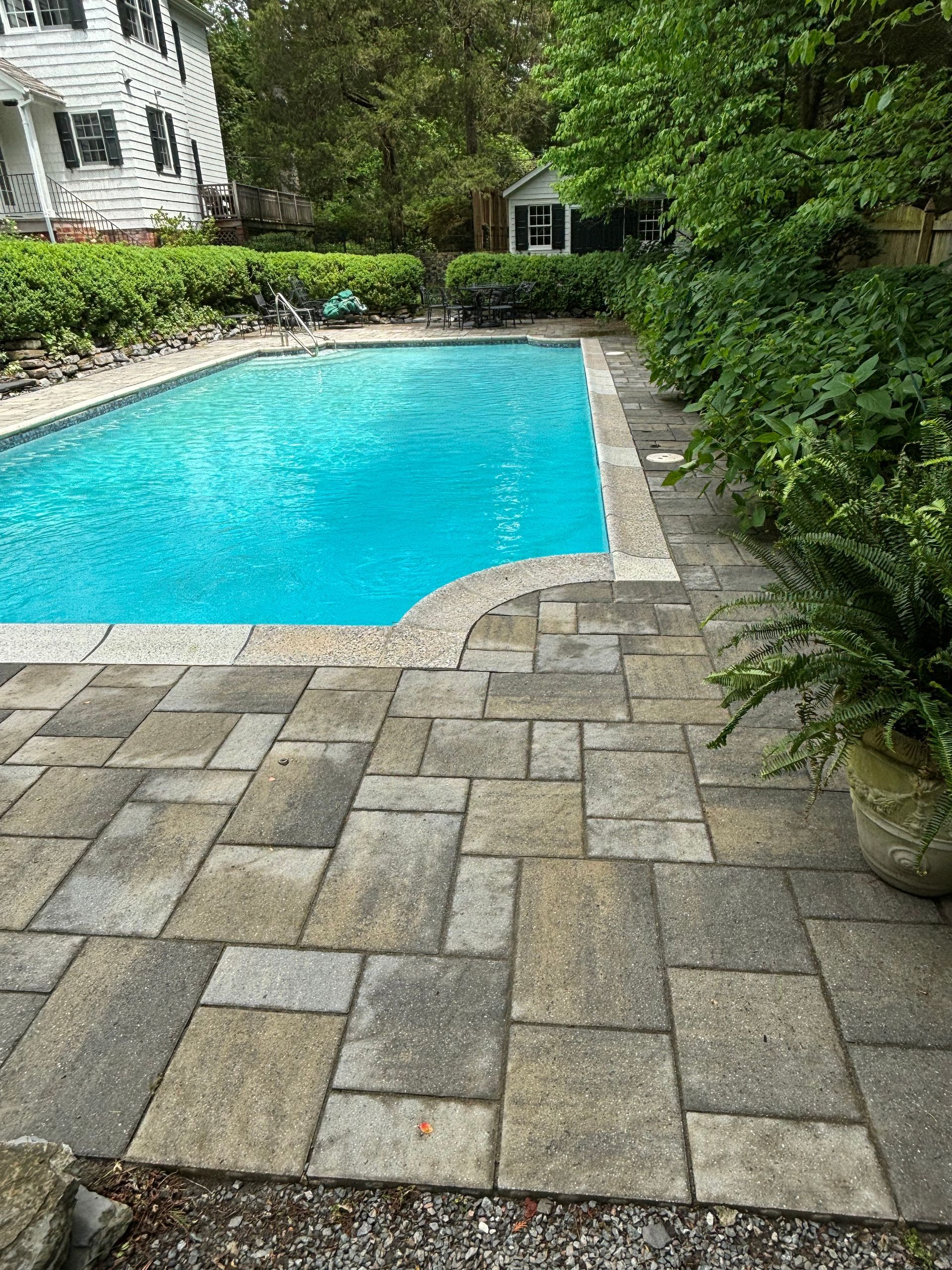 A large swimming pool with a patio in front of it.