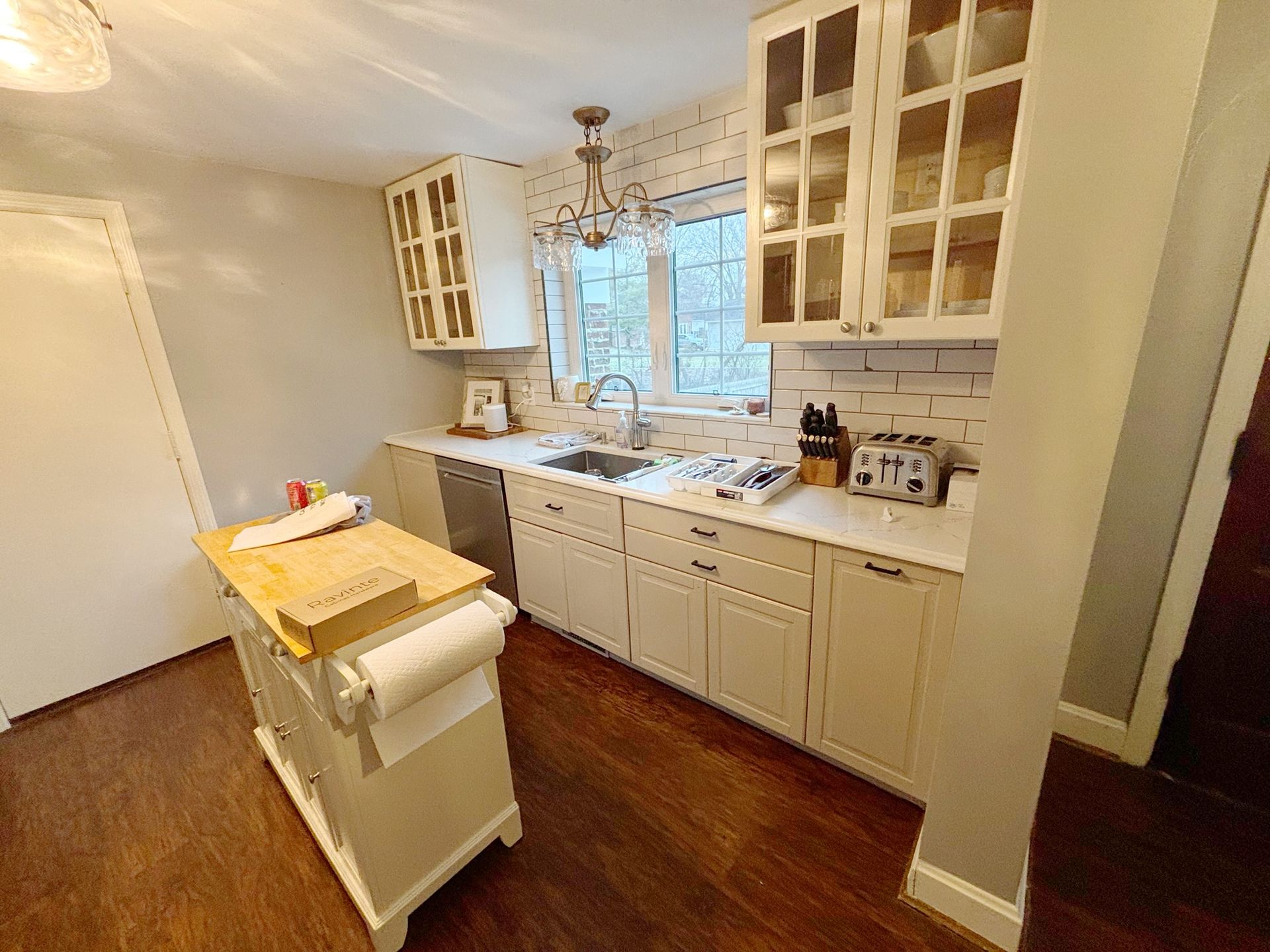 Kitchen with white cabinets, island, and window above the sink.