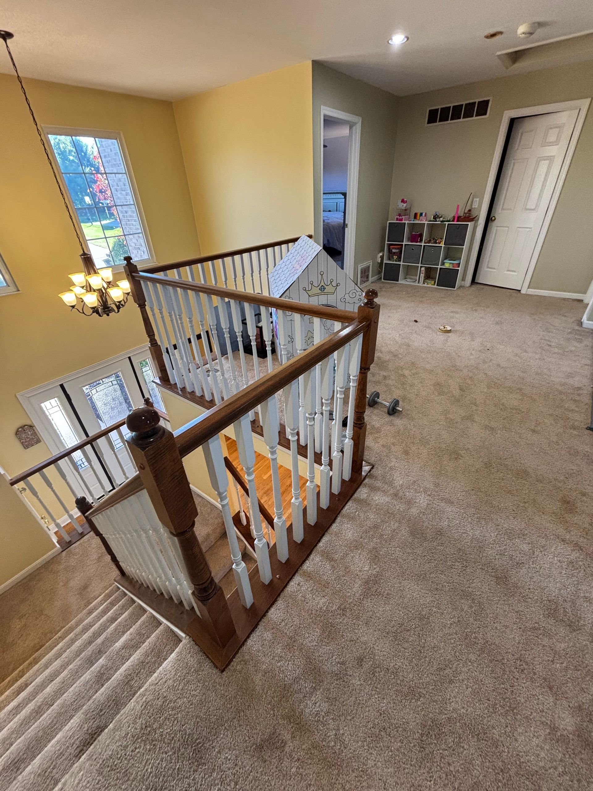 Staircase with wooden banisters, beige carpet, and a view of a second-floor hallway with a door.