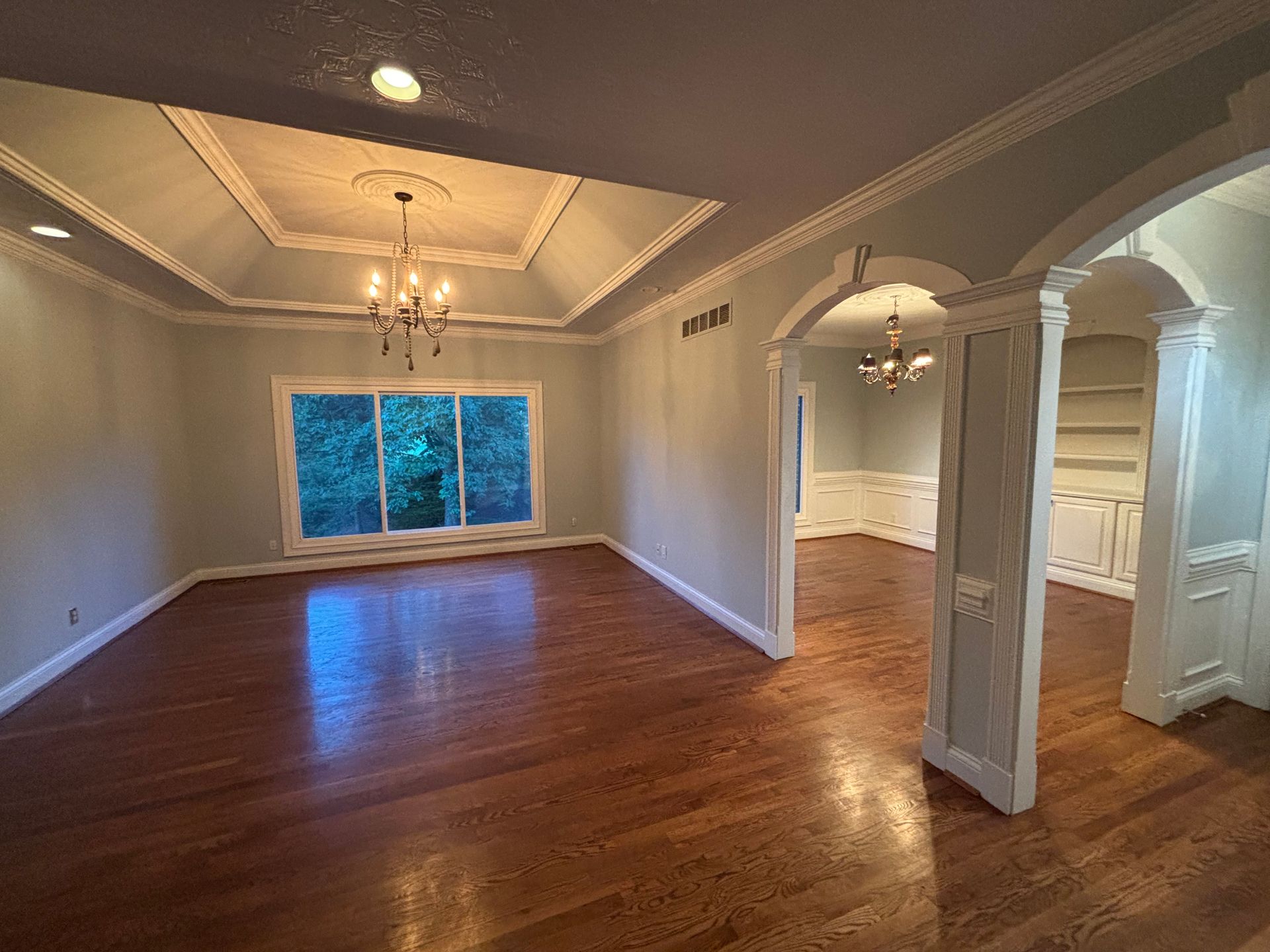 Empty room with wood floors, pale blue walls, and ornate ceiling details.