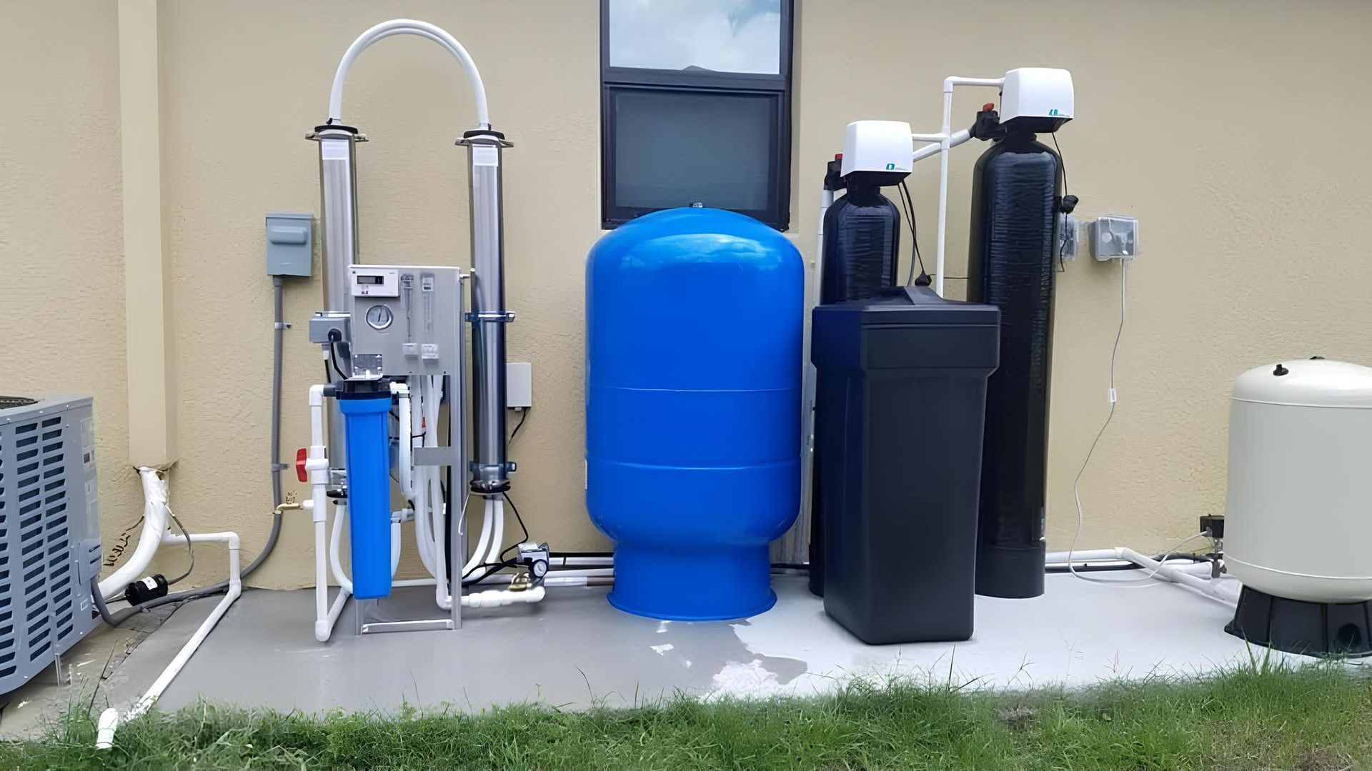 Outdoor water treatment equipment with blue tank, pumps, and filtration units beside a building