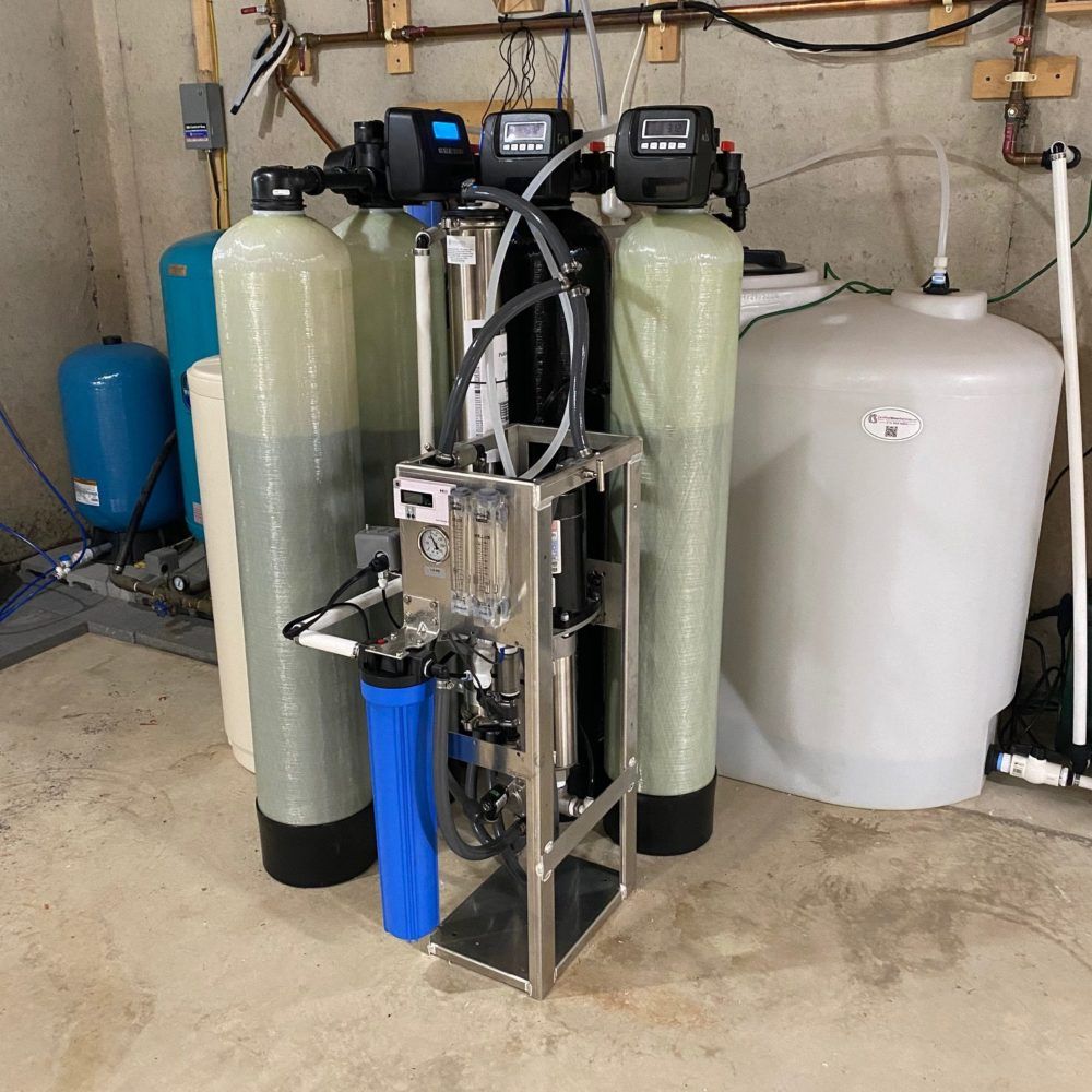 Water filtration system with tanks, pumps, and pipes in a utility room.