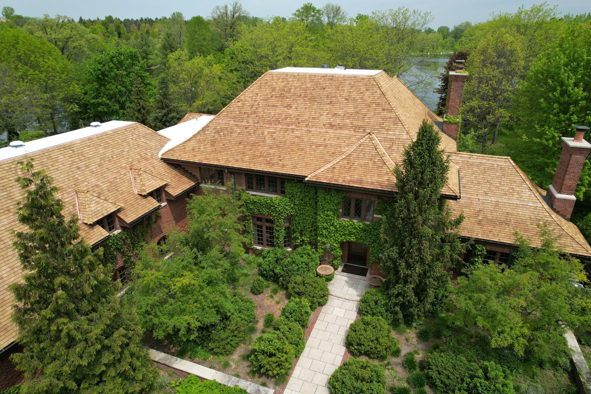 An aerial view of a large house surrounded by trees and bushes.